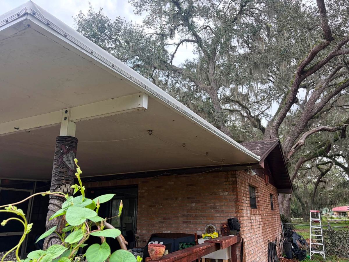 Brick residential building with carport under large oak tree with Spanish moss