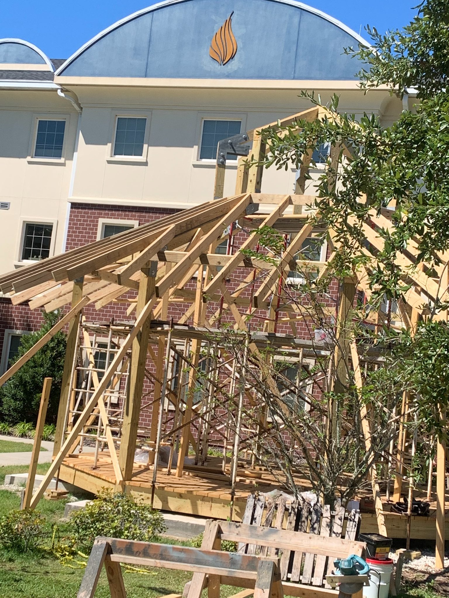 Wooden pergola structure under construction attached to brick residential building