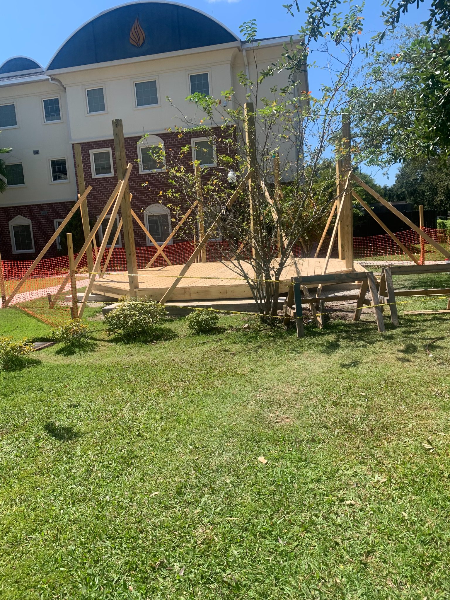 Wooden deck construction in progress with framing and railings, adjacent to brick building with dome roof