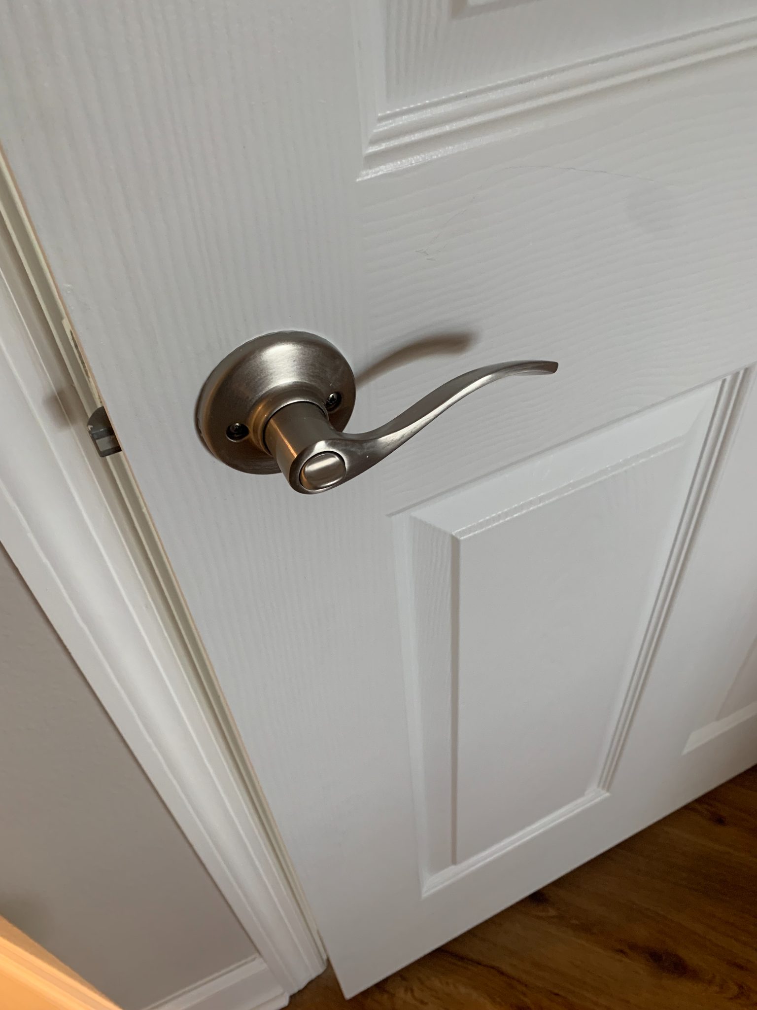 Brushed nickel lever door handle on white six-panel interior door