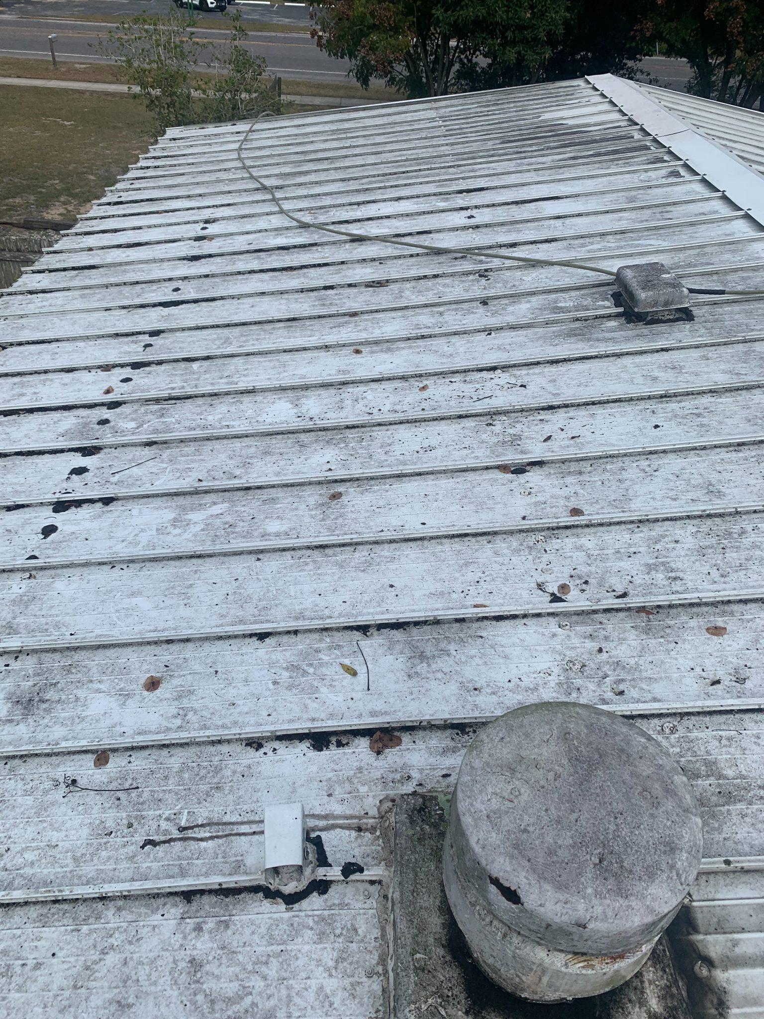 Metal roof with corrugated panels, debris, and concrete pipe penetrations