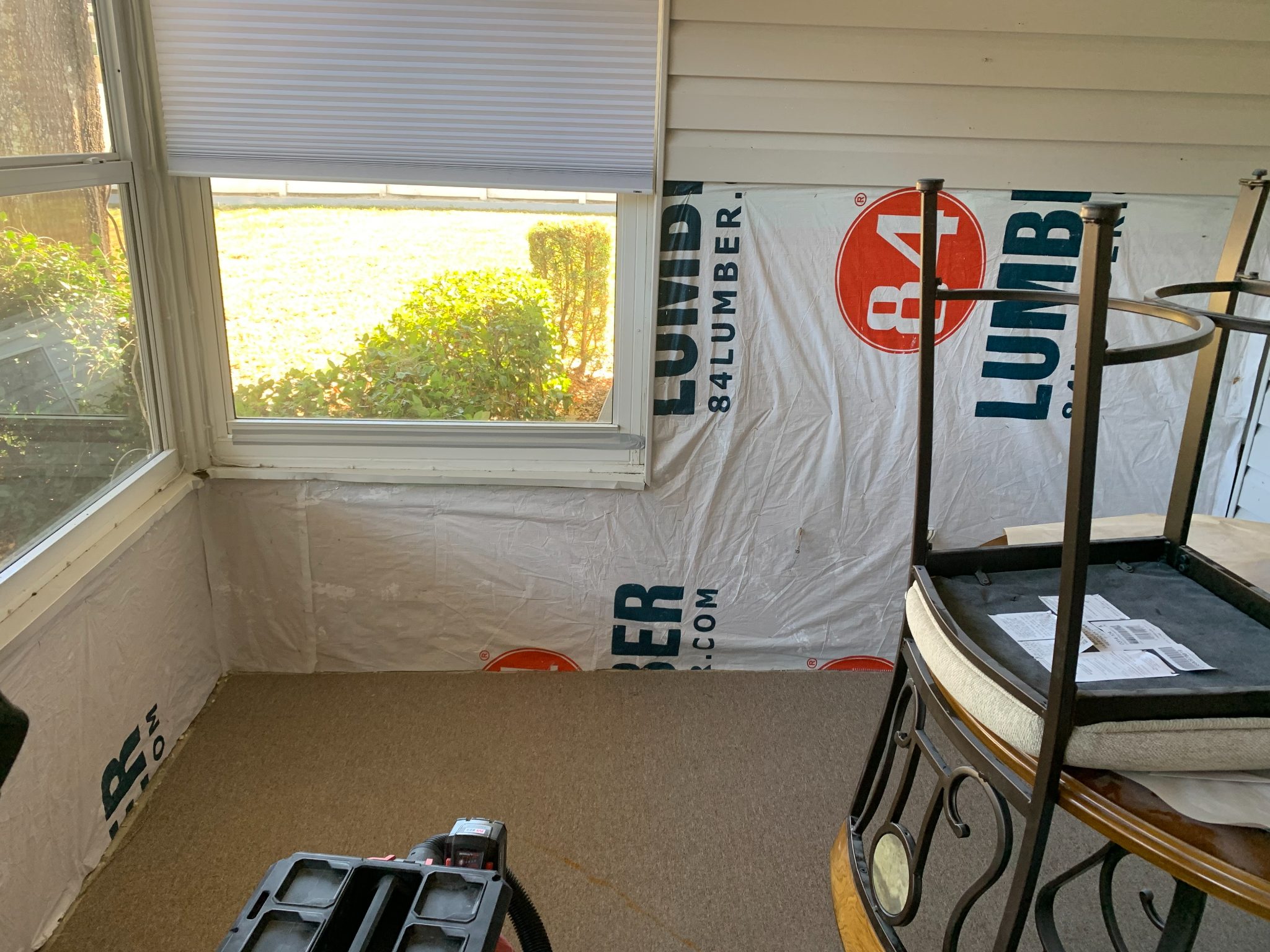Interior room with protective plastic sheeting, windows, and furniture during renovation or construction