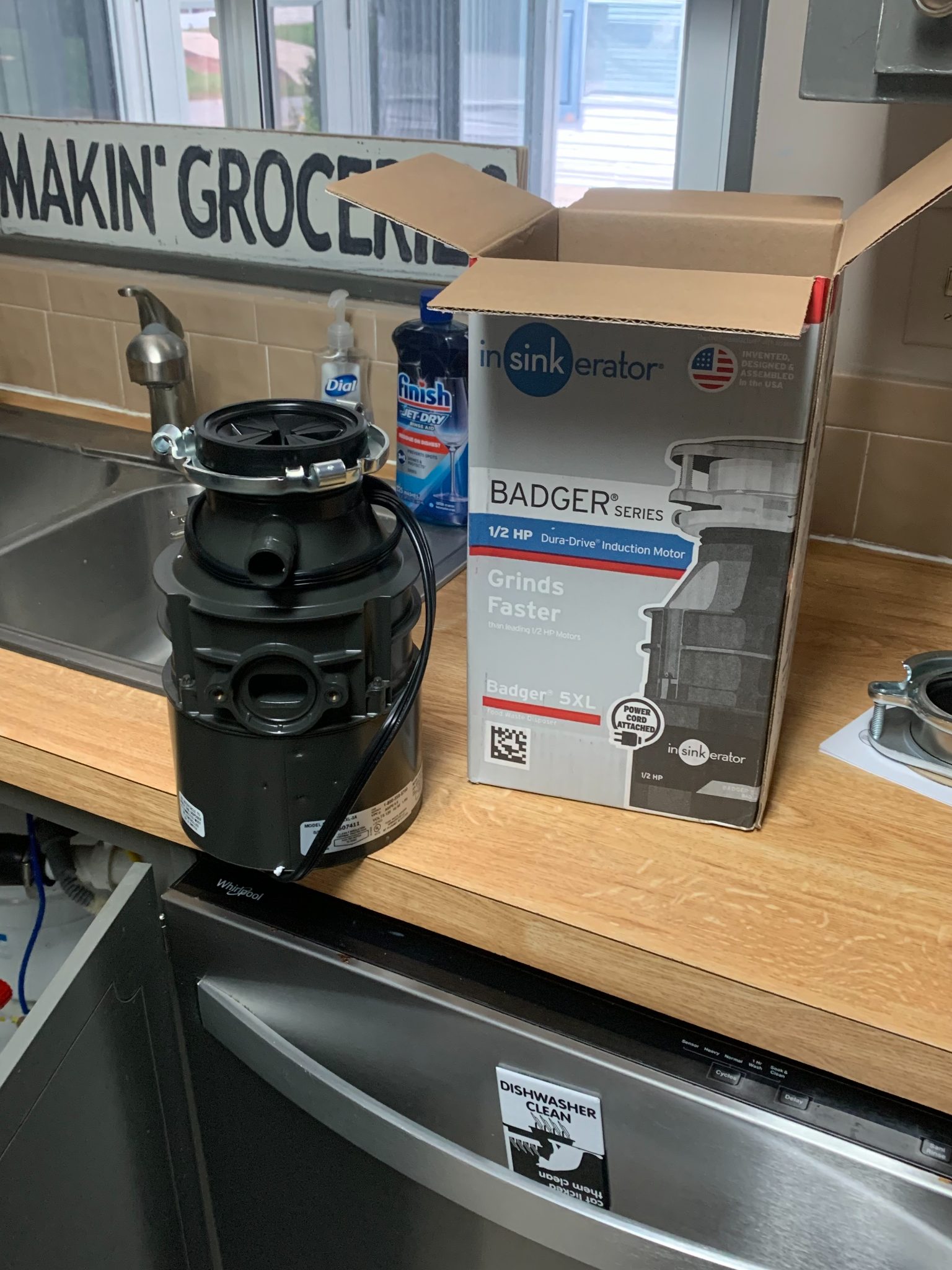 InSinkErator Badger Series 1/2 HP garbage disposal unit next to its cardboard box packaging on a kitchen counter