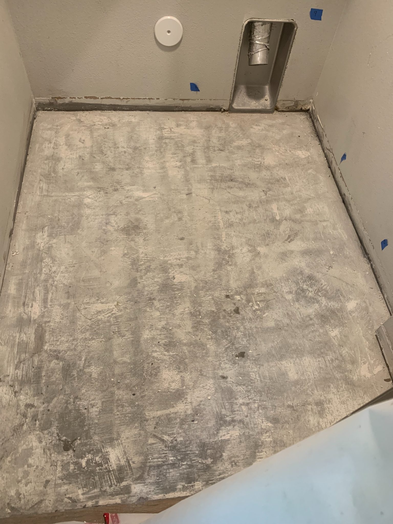 Unfinished concrete floor in empty room with white walls and metal ductwork