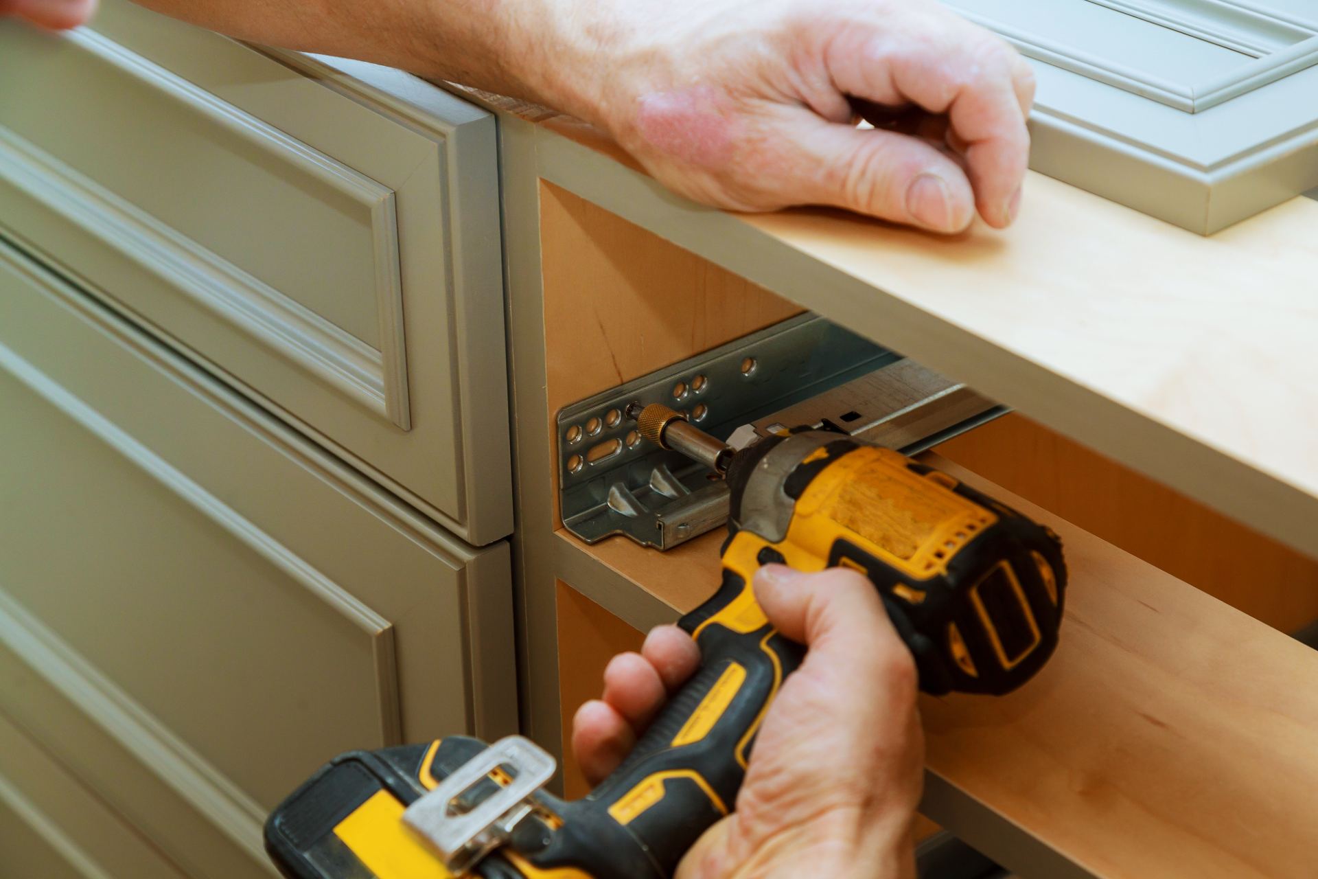 Technician installing cabinet hardware with yellow and black power drill