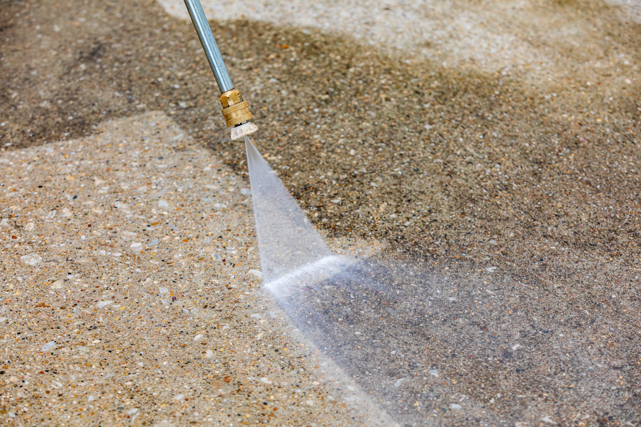 Pressure washer spray cleaning concrete surface with water jet